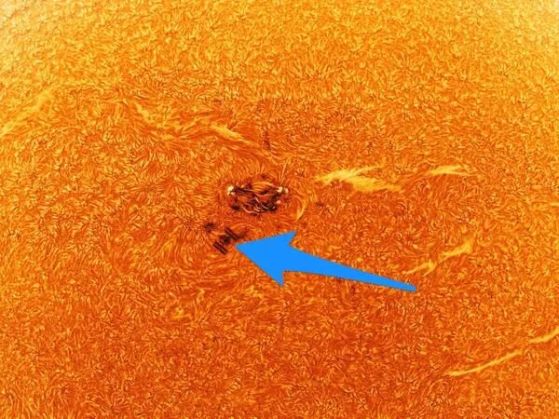 Още по-близко изображение на малък участък от слънцето, показващо по-тъмната зона (слънчево петно) и Международната космическа станция (обозначена със синя стрелка).