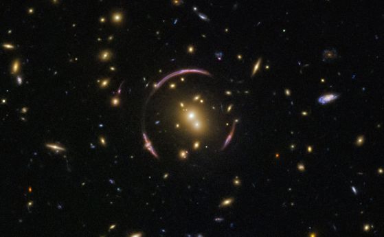 Изображение от Хъбъл на SDSSJ0146-0929, галактически куп, който е достатъчно масивен, за да изкриви сериозно пространство-времето около себе си. Той действа благодарение на масата на видимите звезди и газ, но има и скрито количество тъмна материя