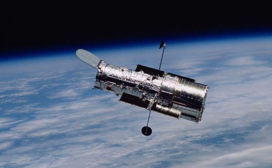 Космическият телескоп Хъбъл на НАСА лети над Земята на заден план след мисия за обслужване през 2002 г. 