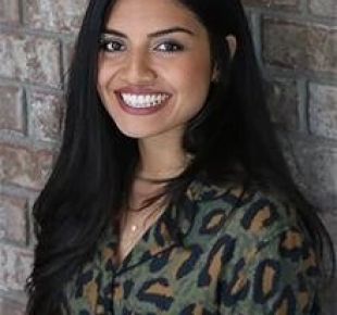 Humsa Venkatesh standing against a brick wall.