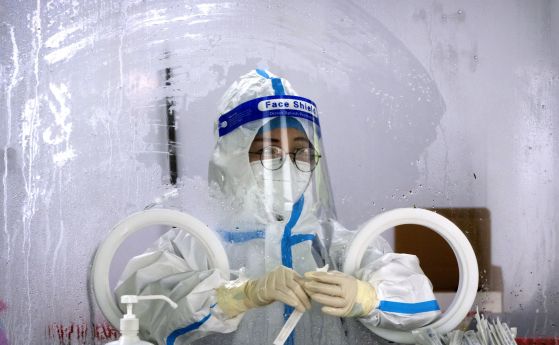 Служител, облечен в защитен костюм, чака да направи тест за COVID-19 в център за тестване на коронавируси в Пекин, сряда, 6 юли 2022 г. На жителите на части от Шанхай и Пекин бе наредено да преминат през допълнително тестване за COVID-19 след откриването 