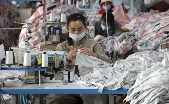 Шивачка с маска на лицето шие в текстилна фабрика в окръг Хуимин в източната китайска провинция Шандун.