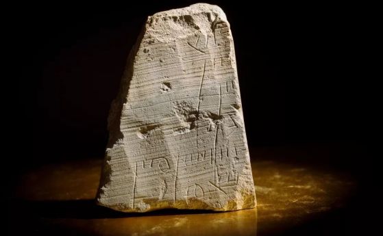 Триъгълна сива каменна плоча, изписана на иврит на черен фон.
