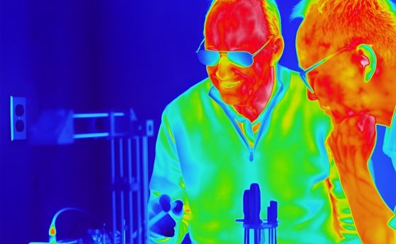 Джън и Граник работят в лабораторията. Тази снимка е направена с инфрачервената камера, която са използвали за своите експерименти. Цветовете измерват температурата. Забележете, че кожата им е топла, а косата им е по-студена.