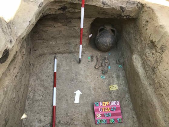 Снимка на погребение, на която се виждат ваза с кости и мерителни лати