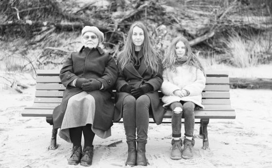 дете, зряла и възрастна жена седят на пейка