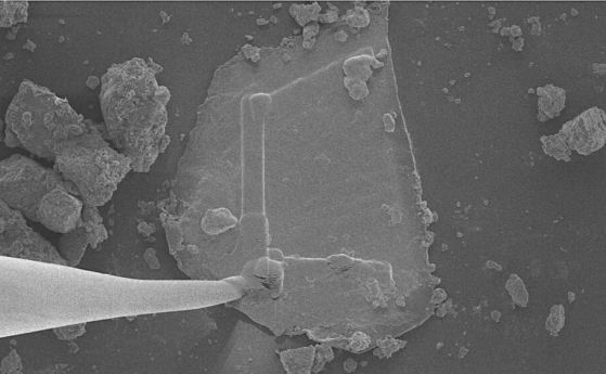 Платинена армировка (формата "L" на пробата) и волфрамова микроигла (вляво), прикрепена към пробата от "дъвка" от астероид Бену. 