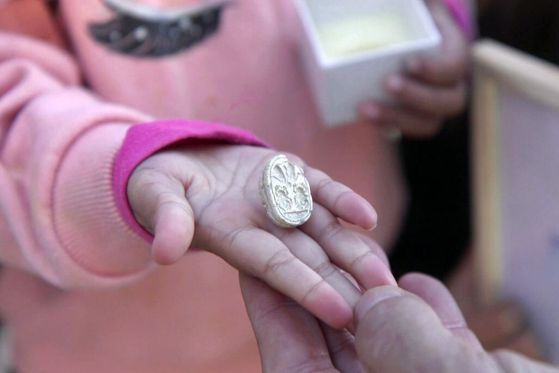 Ръката на малко момиченце държи малък декоративен камък