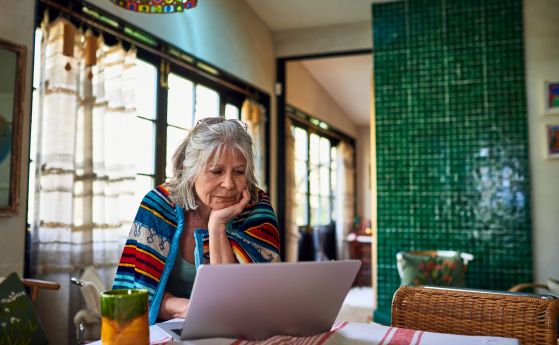 Сивокоса жена, работеща в вкъщи с лаптоп