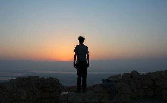 Силует на човек в планината на фона на залез.