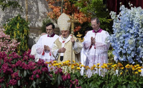 Папа Бенедикт XVI, придружаван от свещеници, върви през цъфналите цветя в двора на базиликата 