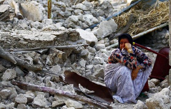 Жена седи върху отломките от сграда, разрушена от силното земетресение в Иран на 9 април 2013 г. Снимка: EPA/БГНЕС