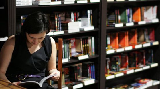 Млада жена чете книга в библиотека. Снимка: БГНЕС