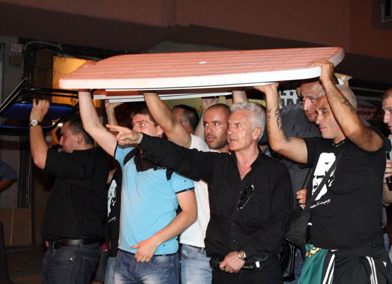 Симпатизанти на Атака държат маса над Волен Сидеров, за да го запазят от хвърляните по него предмети по време на протеста в понеделник. Снимка Сергей Антонов