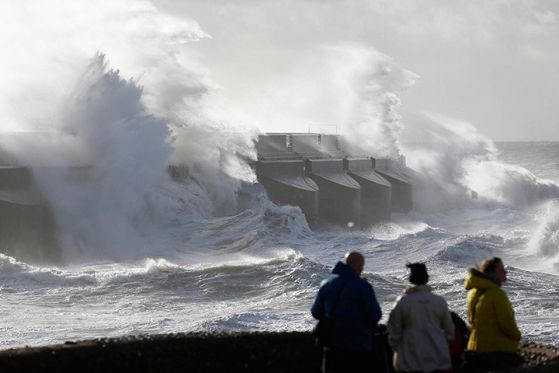 Трима души наблюдават бушуващата буря на британското крайбрежие. Снимка: ЕПА/БГНЕС