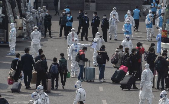 Китайски работници и здравни служители в защитни бели костюми насочват пътници от Ухан към автобуси, които ще ги извозят до домовете им където ще останат под 14-дневна карантина. 8 април 2022 г.