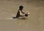 Момче носи хранителна дажба, докато се провира през наводнен район в покрайнините на Пешавар, Пакистан, неделя, 28 август 2022 г. 