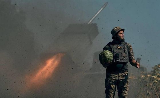 Снимка на украински войник носещ диня в ръка докато зад гърба му