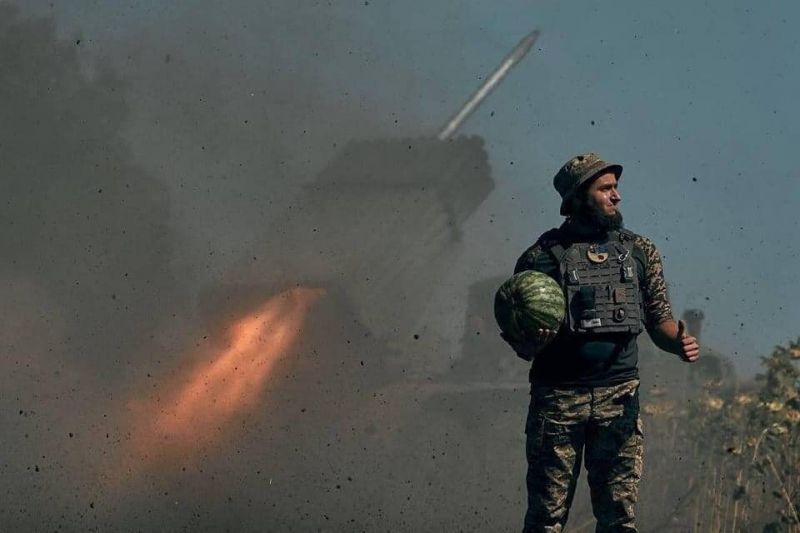 Снимка на украински войник, носещ диня в ръка докато зад гърба му