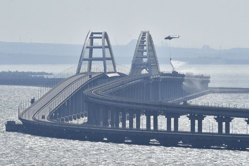 Хеликоптер изсипва вода върху Кримския мост, за да потуши пламъците след взрива на камион на 8 октомври 2022 г.