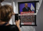 Жена снима плакат със снимки на заложниците в Газа под изображението на министър-председателя Бенямин Нетаняху, който призовава останалите израелски водачи да постигнат споразумение за връщането им у дома. Тел Авив, 21 ноември 2023 г.
