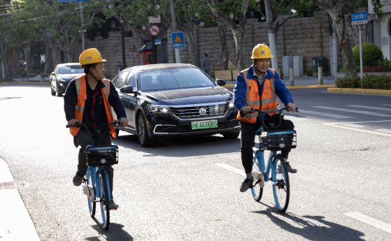 Велосипедисти се движат пред електрически автомобил в Китай