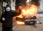 Протестиращ с маска Anonymous пред запалена кола
