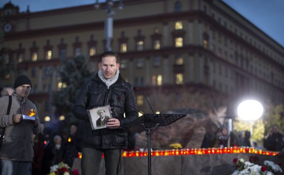 Мъж с портрет на жертва на съветските репресии, а други полагат венци и палят свещи пред мемориал, издигнат пред бившата централа на КГБ в Москва.