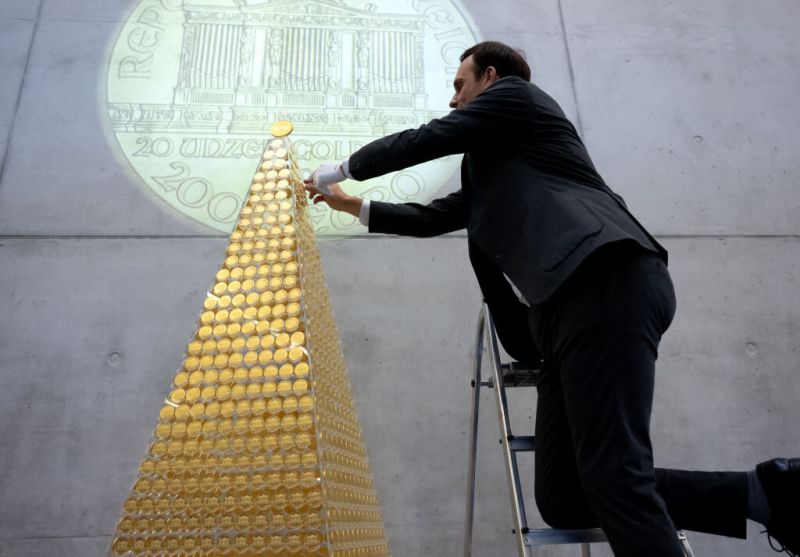 03 December 2024, Bavaria, Munich: Benjamin Summa, employee at pro aurum, places a gold coin in the gold Christmas tree. In cooperation with the Austrian Mint, the precious metal dealer is presenting the gold tree, which consists of 2,024 Vienna Philharmo