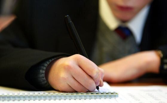 Ученик пише в тетрадка