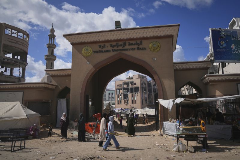 Палестинци минават покрай портата на Ислямския университет в град Газа, който сега е убежище за разселени палестинци, 5 април 2025 г.
